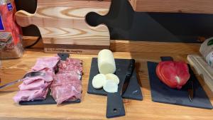 a cutting board with a knife and some meat and an apple at Room4You in Oulx