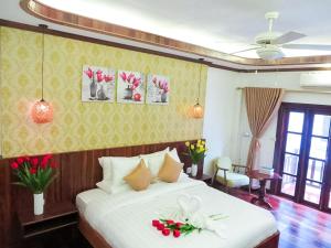 een slaapkamer met een wit bed met bloemen erop bij Mekong Charm Riverside in Luang Prabang