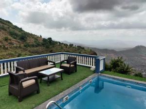 Un balcón con piscina, sillas y mesa. en Hilltop Resort and Agro Tourism Wai, Near Panchgani, en Wai