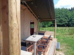 einen Holztisch und Stühle in einem Zelt in der Unterkunft Le Lodge de la Chouette in Quarré-les-Tombes