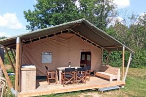 a tent with a table and chairs in a field at Le Lodge de la Chouette in Quarré-les-Tombes