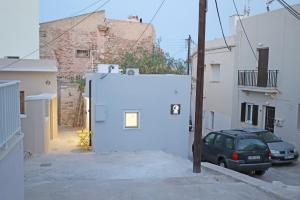 ein Auto parkt auf einem Parkplatz neben einem weißen Gebäude in der Unterkunft Cozy By Syros Bnb in Ermoupoli