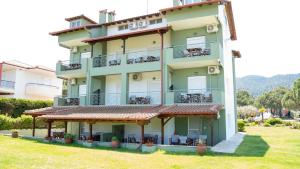 een groot appartementencomplex met een balkon en gras bij Alexandros Hotel Apartments in Vourvourou