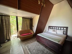 a bedroom with a bed and a chair and windows at Wild root stay- Orchid Chalet in Vythiri