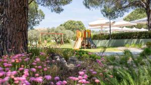 a park with a playground with a slide and flowers at Alexandros Hotel Apartments in Vourvourou