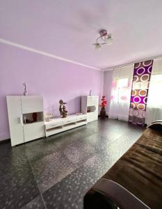 una sala de estar con paredes moradas y muebles blancos. en Harmony Caransebes, en Caransebeş