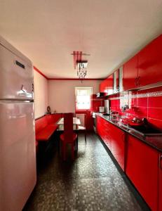 cocina roja con armarios rojos y mesa en Harmony Caransebes, en Caransebeş