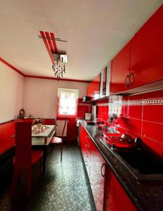 卡蘭塞貝什的住宿－Harmony Caransebes，红色的厨房配有桌子和饭厅