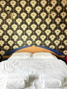 1 dormitorio con cama blanca y papel pintado con motivos florales en Harmony Caransebes, en Caransebeş