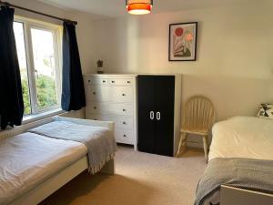 a bedroom with a bed and a dresser and a window at Stunning, Modern and Spacious House - Truro in Truro