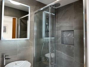 y baño con ducha acristalada y lavamanos. en Stunning, Modern and Spacious House - Truro, en Truro