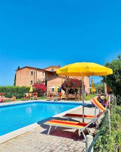 a swimming pool with a yellow umbrella and chairs next to it at Podere Casalpiano in Campiglia Marittima