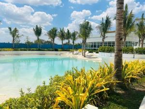 una piscina con palmeras frente a un edificio en LA CASA ALEYKA AZURE NORTH PAMPANGA BALI Tower 518, en San Fernando