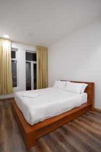 a bedroom with a large bed with white sheets at Richfields in Ooty