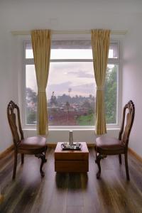 a living room with two chairs and a table and a window at Richfields in Ooty