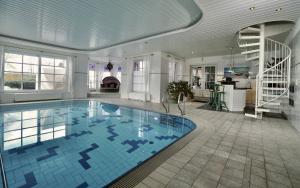a large swimming pool in a house with a staircase at Villa Merle mit privatem Indoorpool in Rühn