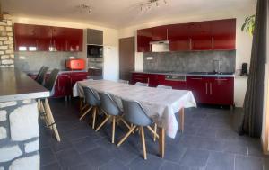 eine Küche mit roten Schränken sowie einem Tisch und Stühlen in der Unterkunft Maison calme 