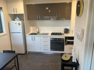 a kitchen with white cabinets and a white refrigerator at Adorable 1 bedroom Unit in Coombs in Weston Creek