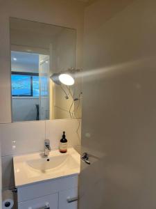 a white bathroom with a sink and a mirror at Adorable 1 bedroom Unit in Coombs in Weston Creek