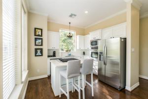 eine Küche mit weißen Schränken und einem Kühlschrank aus Edelstahl in der Unterkunft Montrose Lodge by Dunyha in Houston