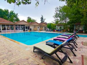 a swimming pool with lounge chairs in front of a building at Paşa Restaurant & Pansiyon in Kemer