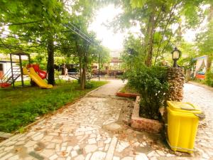 un parc avec une poubelle jaune et une aire de jeux dans l'établissement Paşa Restaurant & Pansiyon, à Kemer