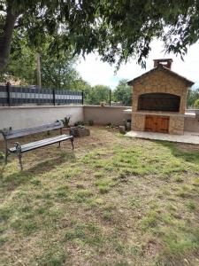 a park bench in a yard with a stone fireplace at Holiday Home Nena in Drniš