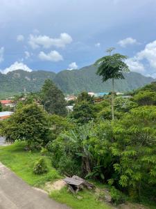 a park with a bench and trees and a mountain at Lodge Phang nga boutique in Ban Khaek