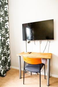 a desk with a television on a wall with a chair at Spångholmen B & B in Mjölby