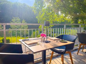 een houten tafel op een terras met stoelen en bloemen bij 2tHEIMAT - Hotel & Restaurant in Morbach