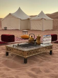 a table in the middle of a desert with tents at Luxury Desert Camp in Al Wāşil