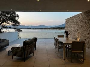 un patio con mesa y sillas y vistas al agua en RESIDENCE Neuve LE GALATEE PIED DANS L'EAU en Porticcio