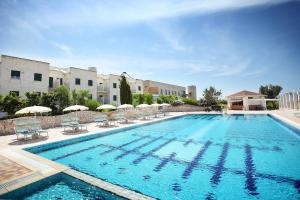 a large swimming pool with chairs and umbrellas at Calanca Apulian Residence in Torre Santa Sabina