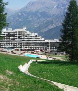 un gran edificio con piscina frente a una montaña en Appartement 4 personnes Puy St Vincent 1700, en Puy-Saint-Vincent