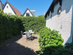 patio con tavolo e sedie accanto a una siepe di Uniek vakantieverblijf Den Burg a Den Burg
