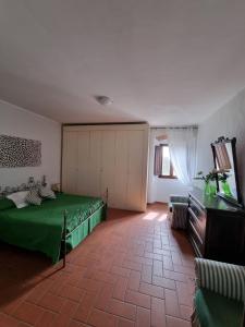 テッラヌオーヴァ・ブラッチョリーニにあるPodere San Lorenzoの緑のベッドと窓が備わる広い客室です。