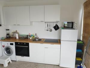 a kitchen with white cabinets and a washer and dryer at Summer cottage with breathtaking view in Zečevo