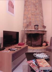 a living room with a fireplace and a tv at Villa Olympia Skafidia in Skafidia