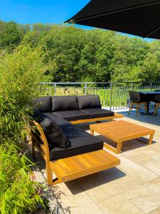un patio con sofás, mesas y una sombrilla en 2tHEIMAT - Hotel & Restaurant en Morbach