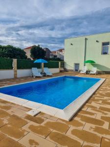 a pool with chairs and umbrellas next to a building at Villa Danijela in Janjina