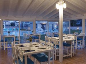 a dining room with tables and chairs and windows at Mara Bahçe Alacati in Alaçatı