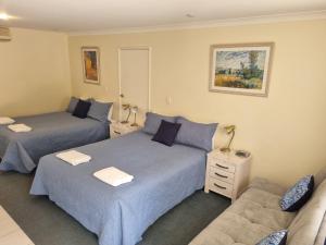a bedroom with two beds and a couch at Emu Point Motel in Albany