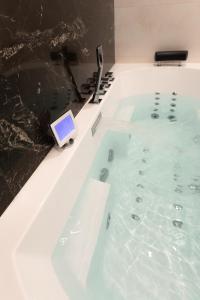 a bath tub filled with water with a tablet in it at Suite Montrachet 4 personnes vue cathédrale 1 Place de parking in Dijon