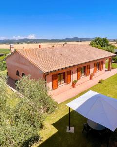 a house with an umbrella in front of it at Podere Casalpiano in Campiglia Marittima