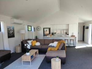a living room with a couch and a kitchen at Beautiful Home with Parking 5 Mins to One NZ Stadium in Christchurch