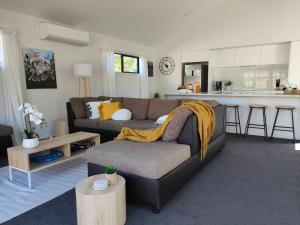 a living room with a couch and a kitchen at Beautiful home near everything! in Christchurch