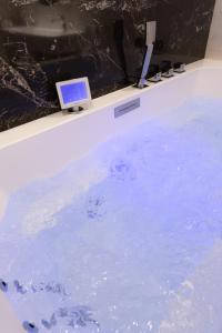 a bath tub filled with blue water with a laptop on it at Suite Romanée 6 personnes vue Cathédrale 2 Places de parking in Dijon