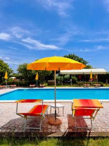 una mesa y 2 sillas con una sombrilla junto a la piscina en Podere Casalpiano, en Campiglia Marittima