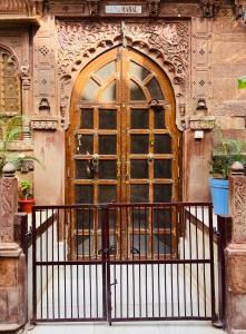 a large wooden door on a building with a fence at Juna Mahal Boutique Home Stay in Jodhpur