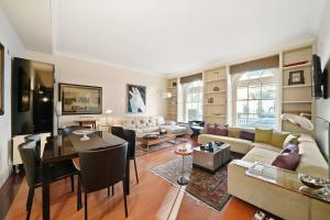 ein Wohnzimmer mit einem Sofa und einem Tisch in der Unterkunft Three Bedroom Apartment in Sloane Square in London